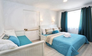 Una habitación de hotel con cama, mesitas de noche y ventana con cortinas.