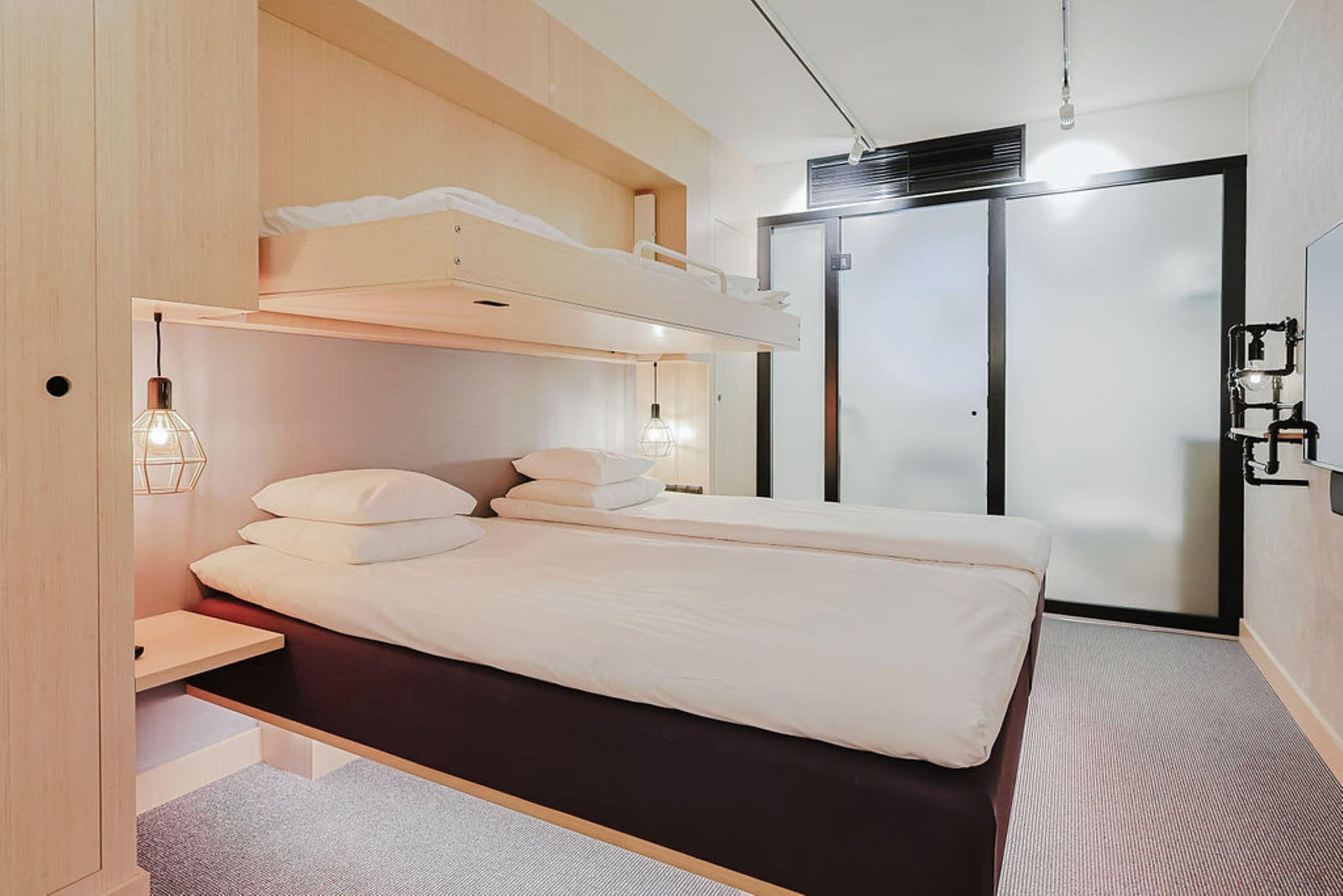 Ein modernes Schlafzimmer mit Etagenbett, Nachttisch, Lampe und Kleiderschrank.
