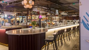 Una zona de bar con una barra curva, taburetes y lámparas colgantes.