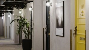 Un pasillo con una planta en maceta, una puerta con un cartel y una puerta amarilla con el número 137.