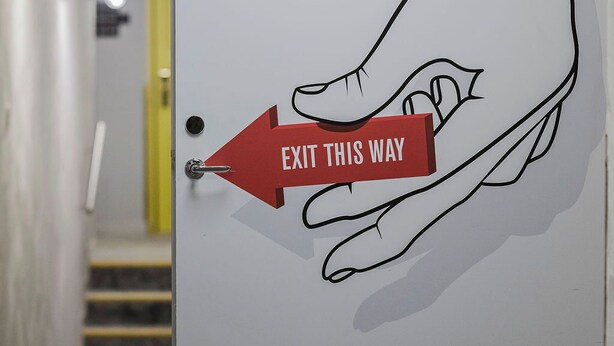 A hand pointing towards an exit sign on a door. - Hotel With Urban Deli (Stockholm)