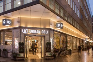 Az Urban Deli épületének külső megjelenése: modern homlokzat, nagy ablakok, és egy kerékpár, ami az épület előtt parkol.
