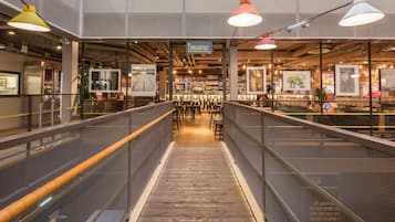 A modern interior with a central staircase leading to a breakfast area, surrounded by seating and artwork.