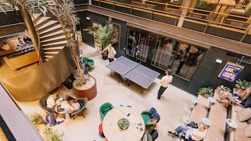 A multi-level indoor space with a ping pong table, seating areas, and a staircase.