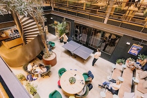A multi-level indoor space with a ping pong table, seating areas, and a staircase. - Hotel With Urban Deli (Stockholm)