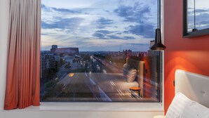 Une pièce dotée d’une grande fenêtre donnant sur un paysage urbain et un pont.