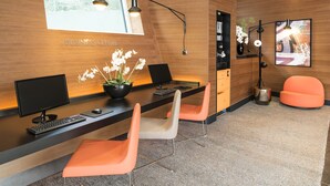 Un centre d’affaires moderne équipé de deux bureaux, d’ordinateurs et de chaises orange.
