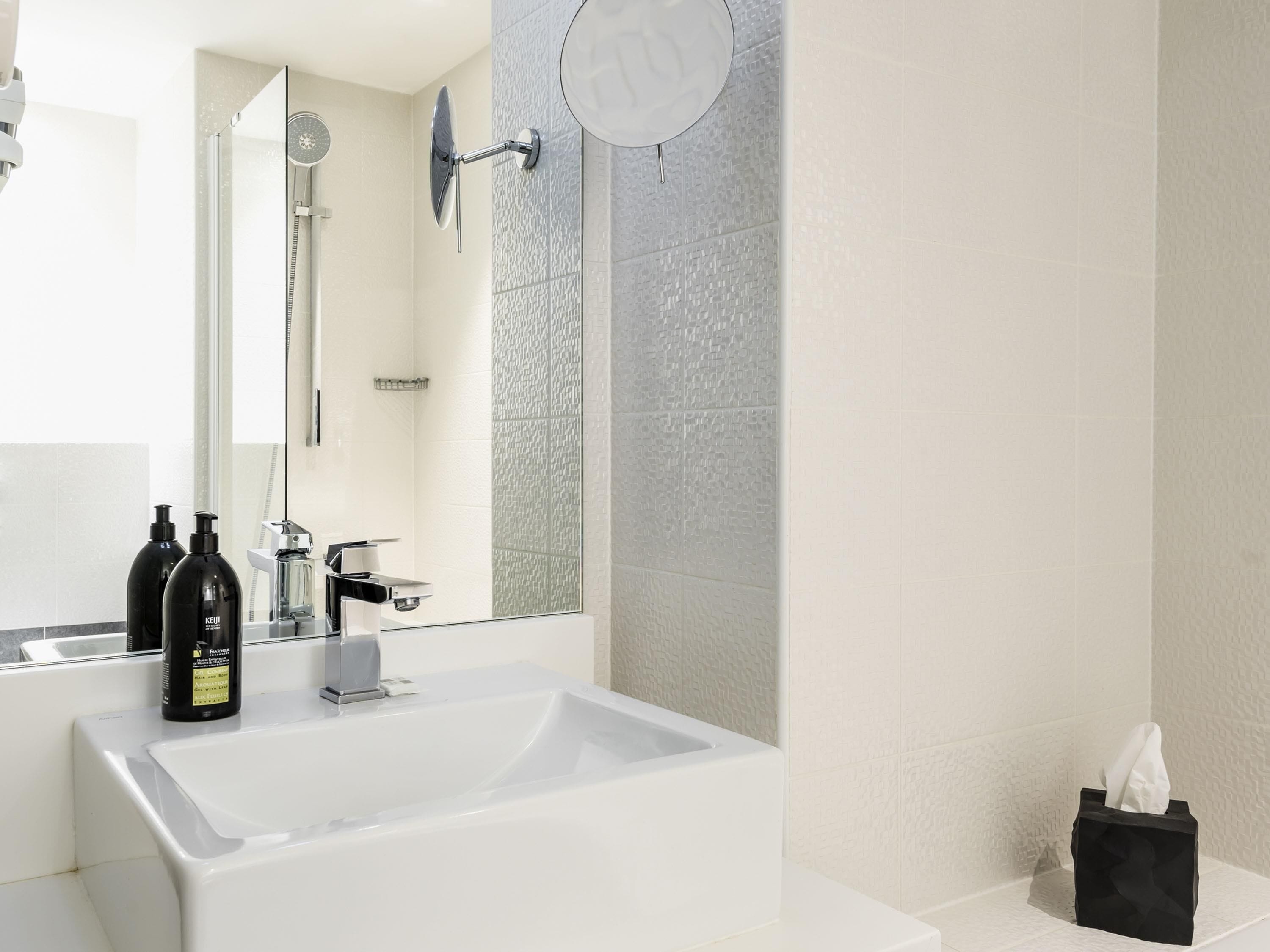 Ein modernes Badezimmer mit einem großen weißen Waschbecken, einer Handbrause und einem Spiegel.