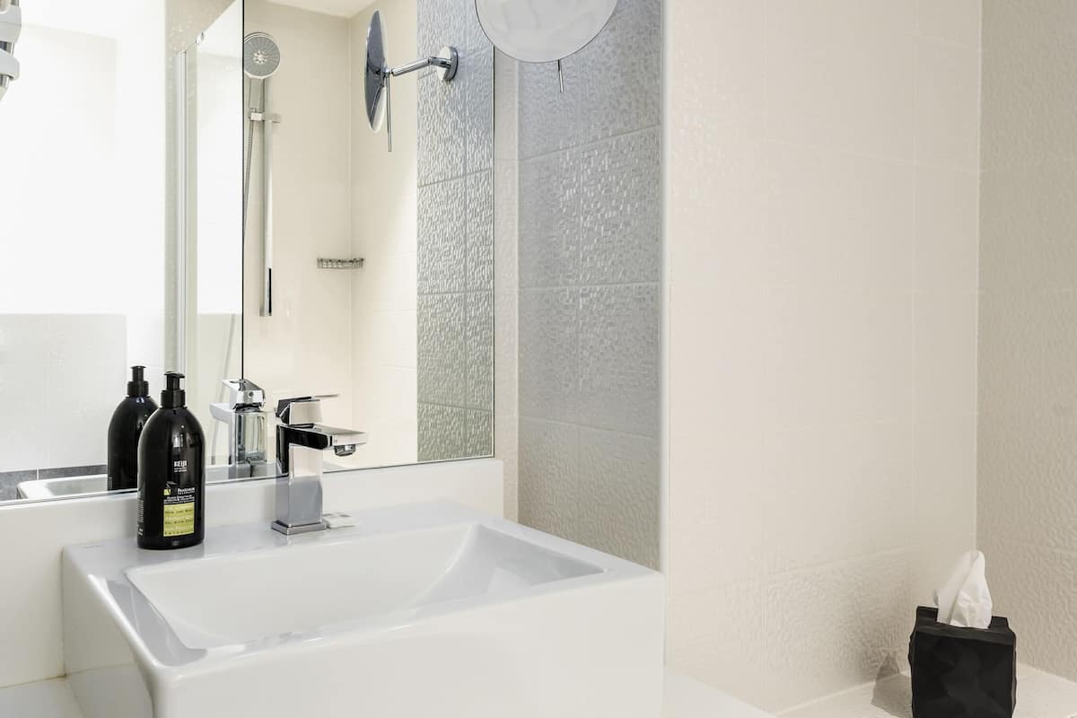 Ein modernes Badezimmer mit einem großen weißen Waschbecken, einer Handbrause und einem Spiegel.