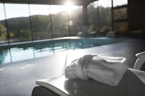 A poolside area with a towel on a chair, a clear view of the pool, and a sunlit background. - Prazer da Natureza Resort & SPA (Caminha)