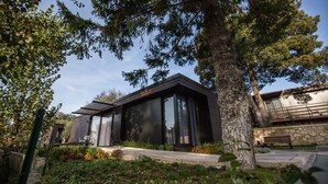 A modern house with large windows, a stone wall, and a bench. - Prazer da Natureza Resort & SPA (Caminha)