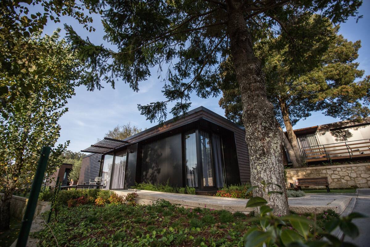 A modern house with large windows, a stone wall, and a bench.