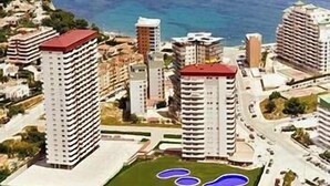 Un grand hôtel avec de nombreux étages, un toit rouge et une vue sur la mer.