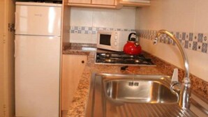 Une cuisine compacte équipée d’un réfrigérateur, d’un four à micro-ondes, d’une cuisinière et d’un évier.