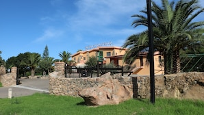 Un hotel con fachada de piedra, palmeras y un cielo azul despejado.