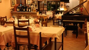 Un restaurante con varias mesas, sillas, un piano y una zona de bar con botellas de vino.