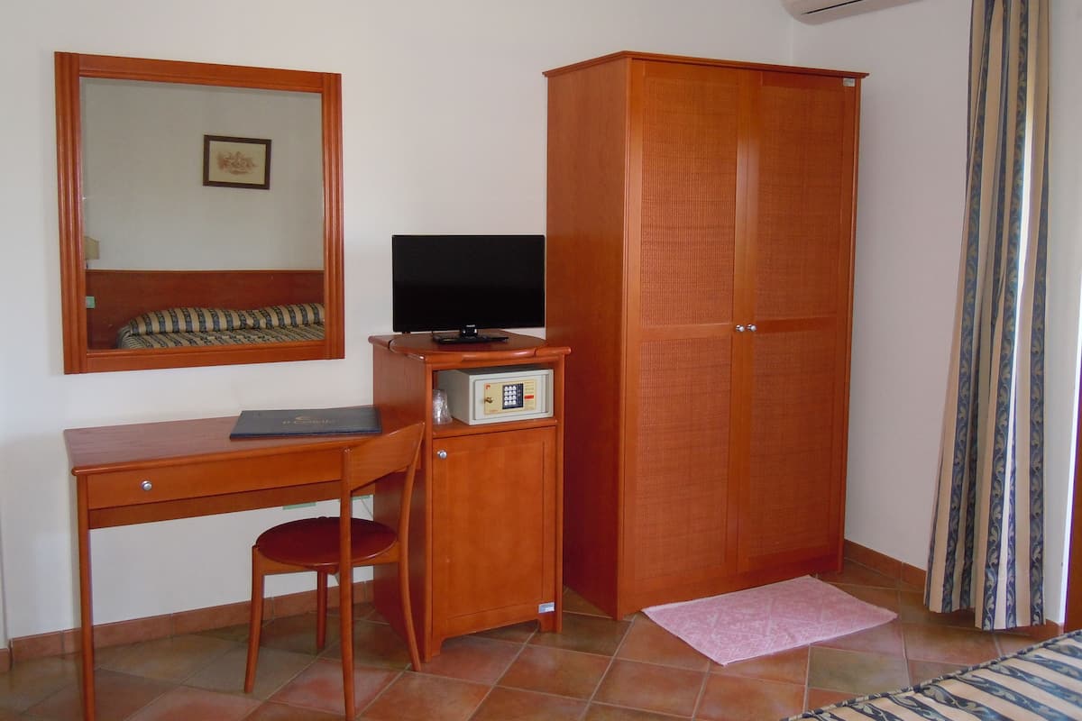 A room with a wooden desk, chair, and wardrobe.
