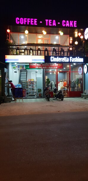 A storefront with neon signs for 'Coffee - Tea - Cake' and 'Cinderella Fashion'. - Thuy - Gunter Garden Bungalow (Mui Ne)