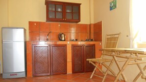 A compact kitchen with a refrigerator, a stove, and a wooden cabinet. - Thuy - Gunter Garden Bungalow (Mui Ne)