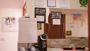 A hotel room with a white desk, a coffee maker, a clock, and various wall decorations including a map and framed certificates. - Guest House Brianza Room (Milan)