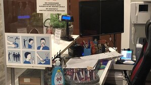 A reception desk with a sign indicating a sanitized room, a computer monitor, a phone, and various office supplies. - Guest House Brianza Room (Milan)