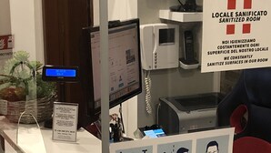 A reception desk with a digital display, a phone, and a sign indicating a sanitized room. - Guest House Brianza Room (Milan)