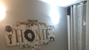 A hotel room with two beds, a wall with artwork, a window with curtains, and a bedside table with a lamp. - Guest House Brianza Room (Milan)