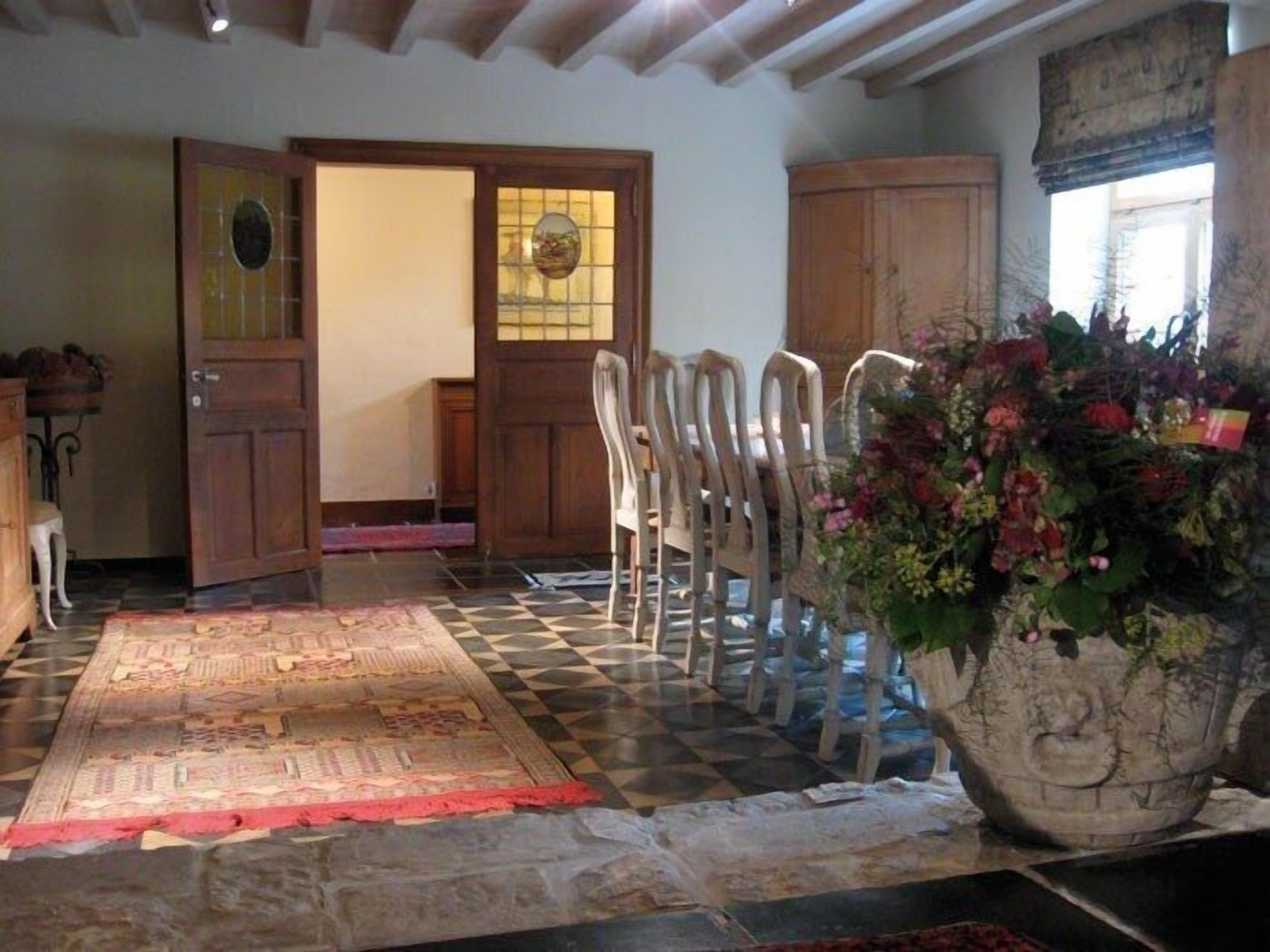 A room with a checkered floor, a large floral arrangement, and a wooden door with glass panels.