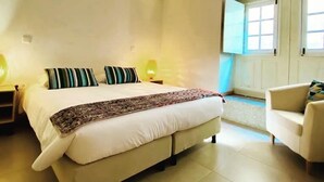 A bedroom with a bed, bedside lamps, a chair, and a window. - Aldeia do Tâmega (Amarante)