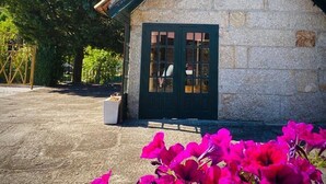 A stone building with a dark green roof and a window with a grid pattern. - Aldeia do Tâmega (Amarante)