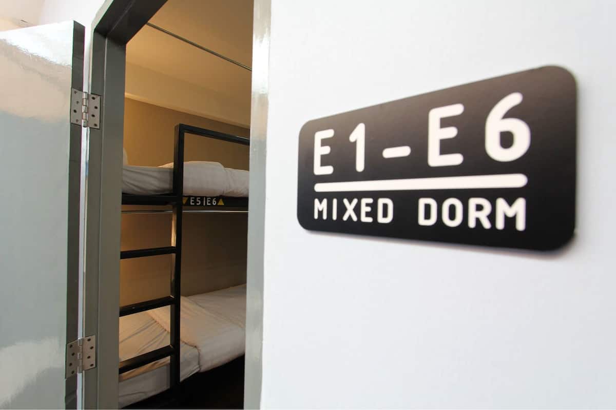 A bunk bed labeled E1-E6 with a sign indicating mixed dormitory accommodation.