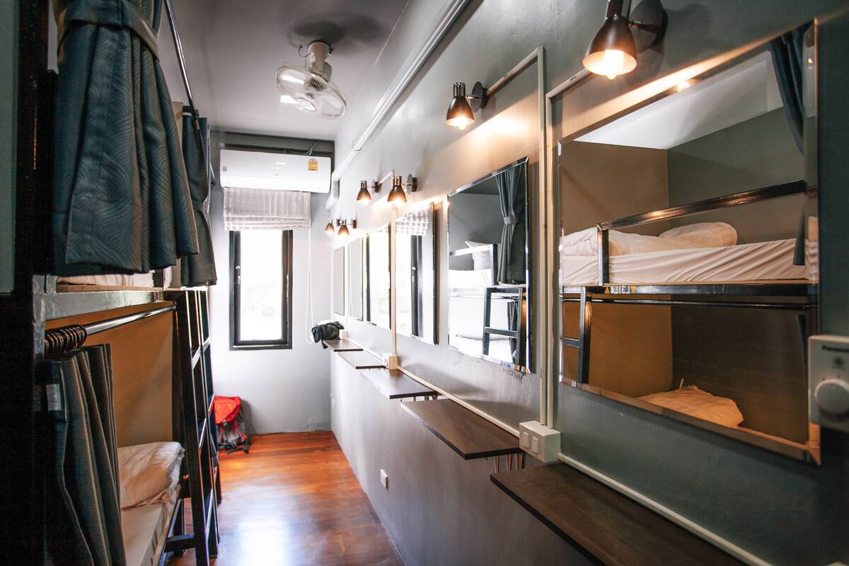 A narrow corridor with bunk beds, a mirror, and a ceiling fan.