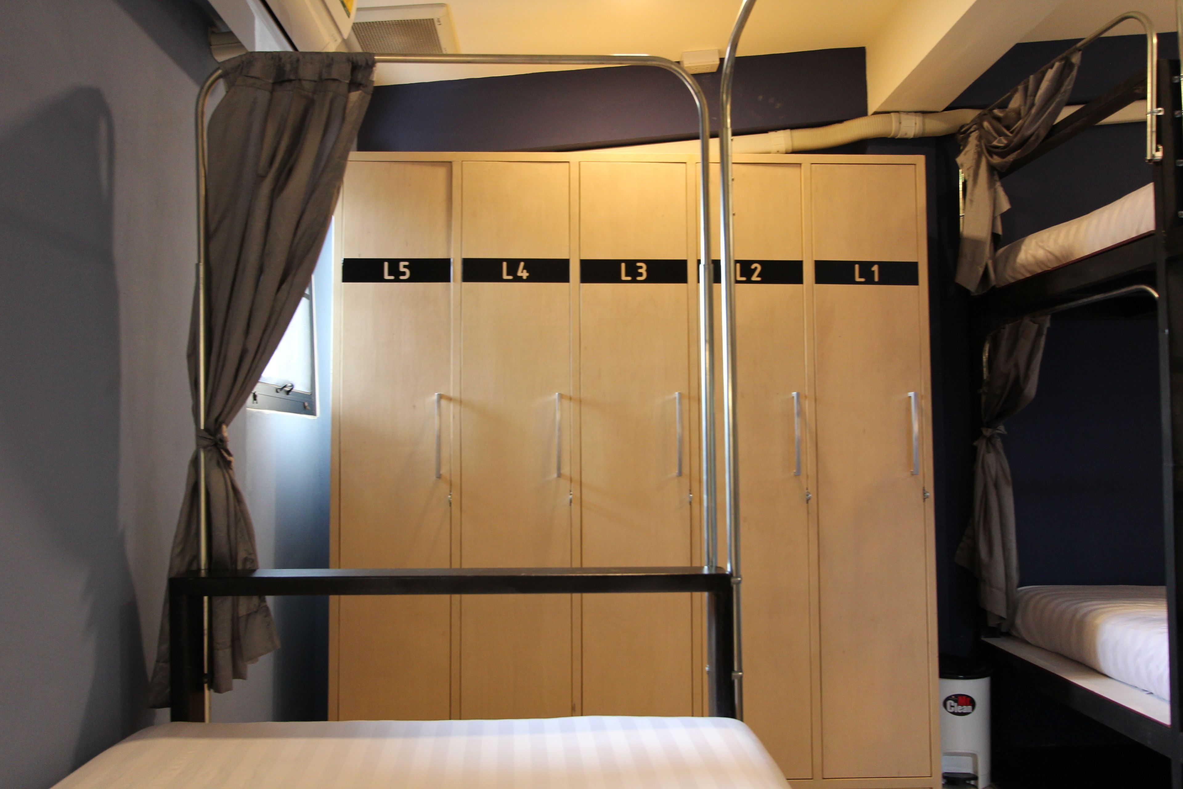 A bunk bed with a metal frame, a single bed with a white mattress, and a wardrobe with multiple compartments labeled L1 to L5.