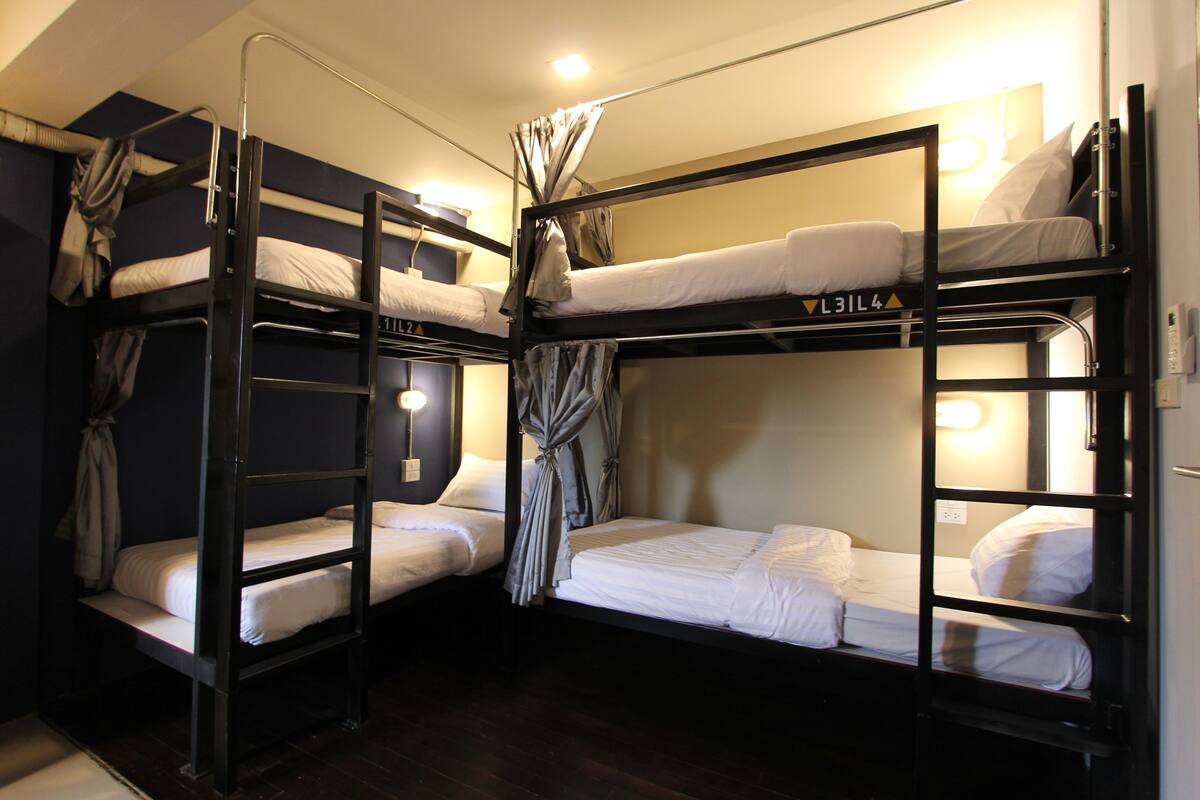 A bunk bed room with three levels, each with a mattress and pillows.