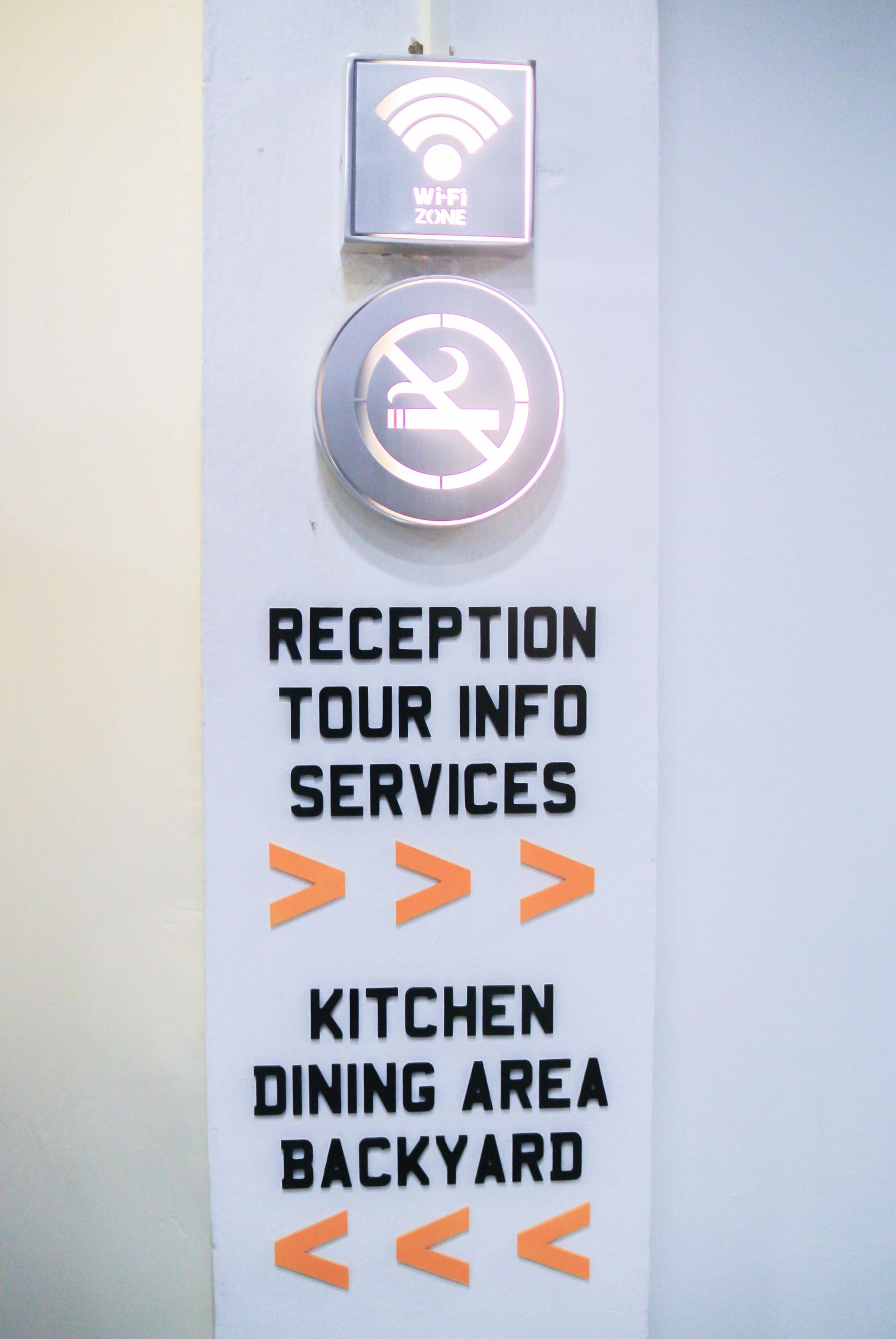A sign with Wi-Fi and no smoking symbols, and directions to reception, tour info, services, and the kitchen dining area in the backyard.