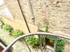 Un balcone con ringhiera in metallo, un muro in mattoni e piante in vaso.