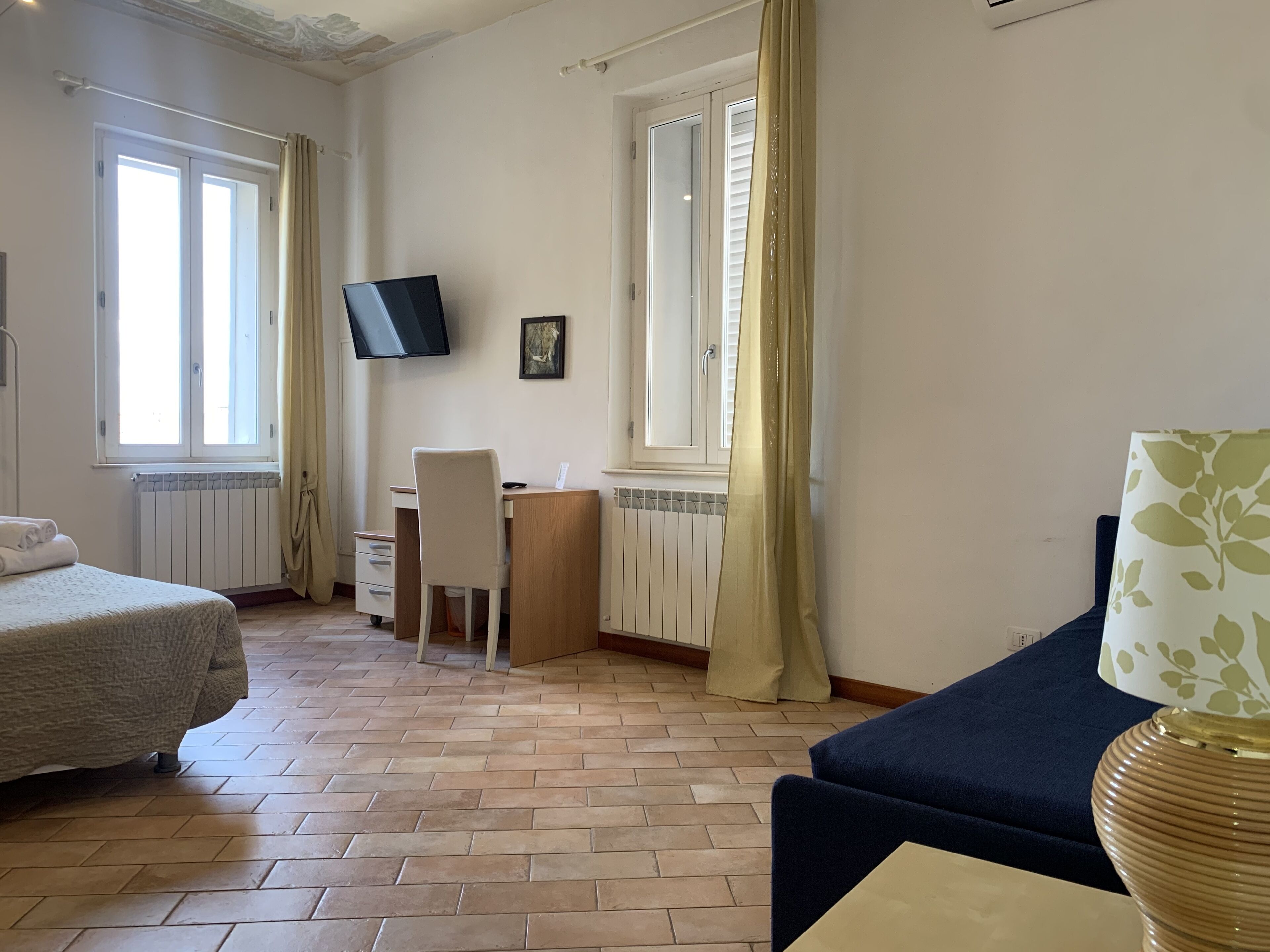 Een hotelkamer met twee bedden, een bureau met stoel, een televisie en een raam met gordijnen.