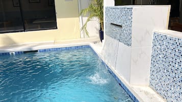 Una piscina con un cartel de 'NO DIVING', un muro con azulejos y una planta en maceta.