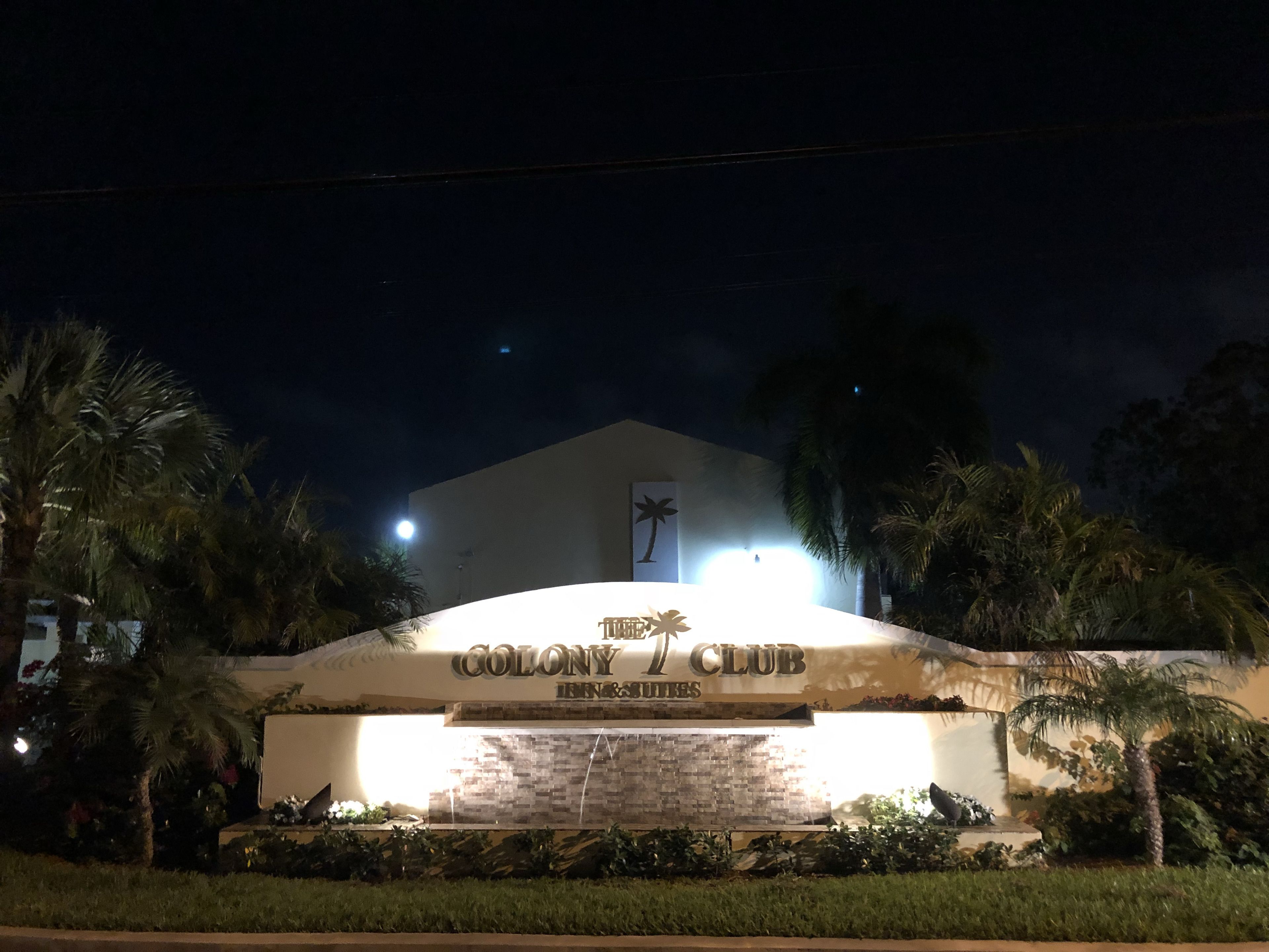 The exterior of the Colony Club with a prominent sign, palm trees, and a well-lit entrance.