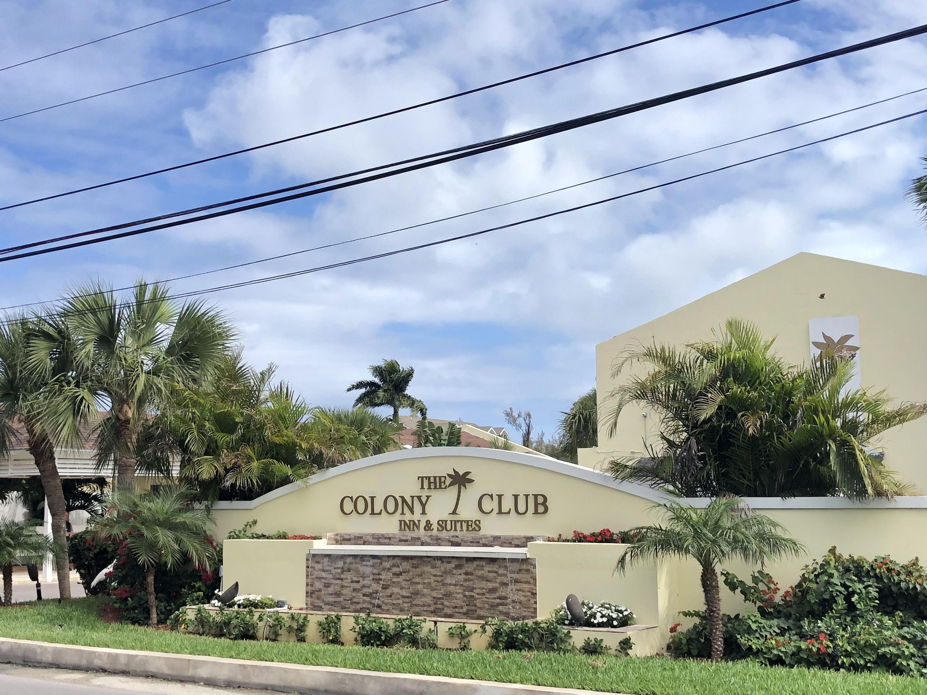 The Colony Club Inn & Suites sign with palm trees and a clear sky.