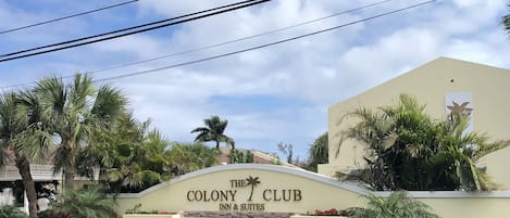 L’enseigne de l’hôtel Colony Club Inn & Suites, avec des palmiers et un ciel dégagé.