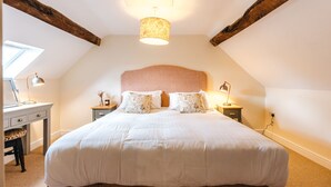 A bedroom with a large bed, wooden beams, a slanted ceiling, and a skylight. - The Pheasant at Neenton (Bridgnorth)