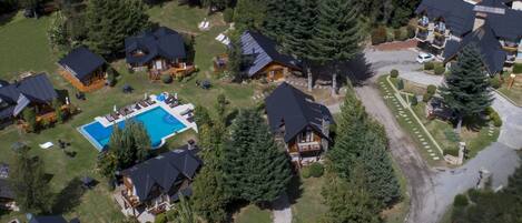 An aerial view of a residential area with multiple houses, a swimming pool, and a well-maintained lawn.