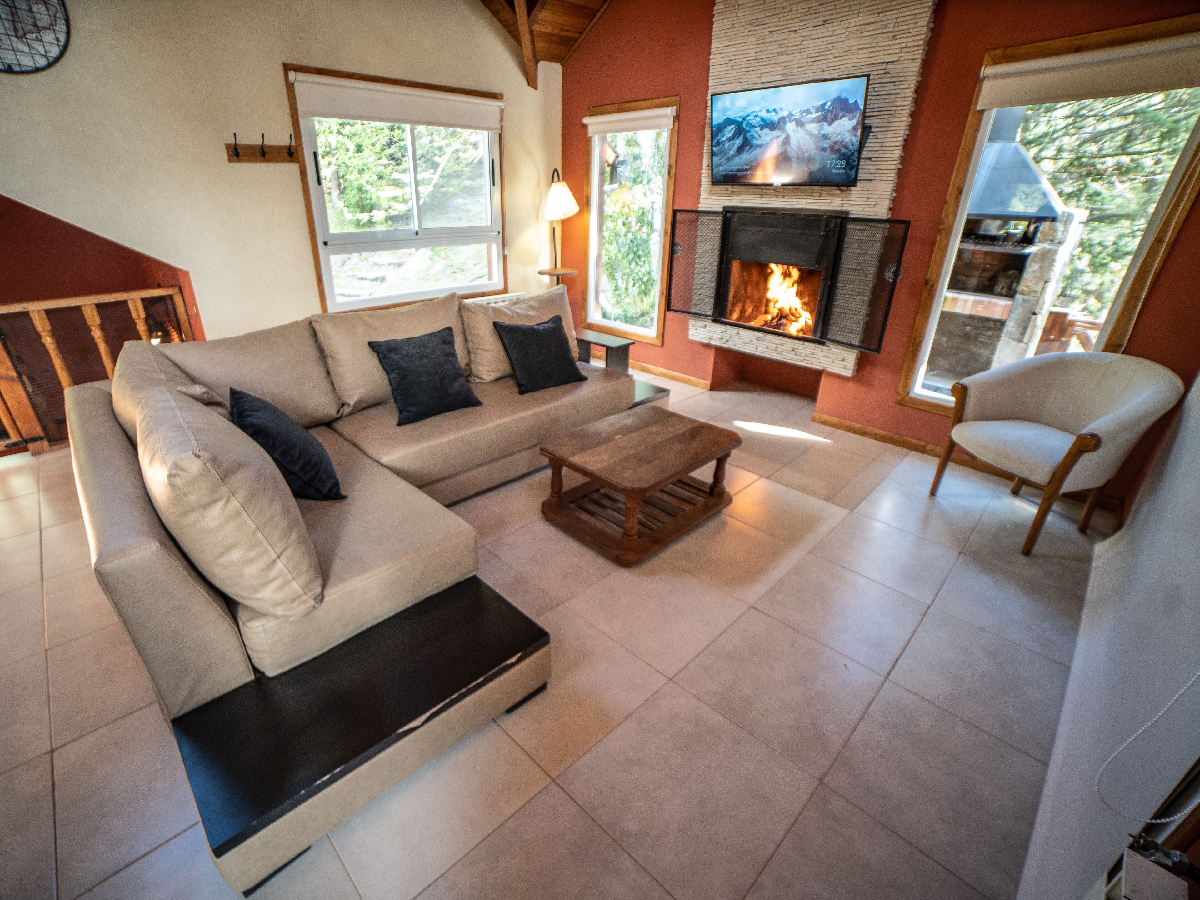 Ein Wohnzimmer mit einem Ecksofa, einem Couchtisch, einem Kamin, einem darüber montierten Fernseher und einem Sessel.
