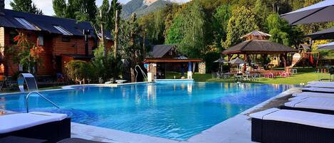 Una piscina cubierta, una piscina al aire libre, sombrillas, tumbonas