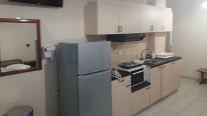 A compact kitchen with a refrigerator, oven, sink, and cabinets. - Harbour View - Oceanis Apartments (Kefalonia)