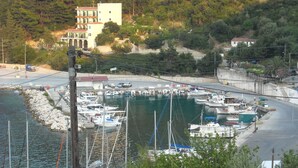 A marina with boats docked, surrounded by buildings and greenery. - Harbour View - Oceanis Apartments (Kefalonia)