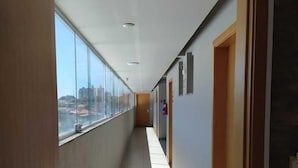 A corridor with a view of the city, a fire extinguisher, and a door on the right. - Front Hotel Expominas (Belo Horizonte)