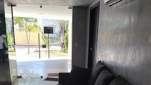 A modern lobby with a dark-colored sofa, a tiled floor, and a view of the outside. - Front Hotel Expominas (Belo Horizonte)