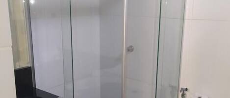 A modern bathroom with a glass-enclosed shower, a black countertop sink, and a toilet.
